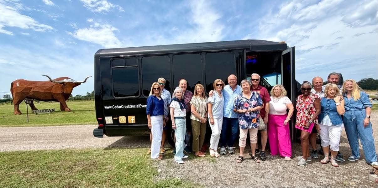 Group with Cedar Creek Social bus and longhorn statue on a wine tour